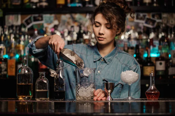 Barman meisje toe te voegen aan de glazen maatbeker een ijsblokjes — Stockfoto