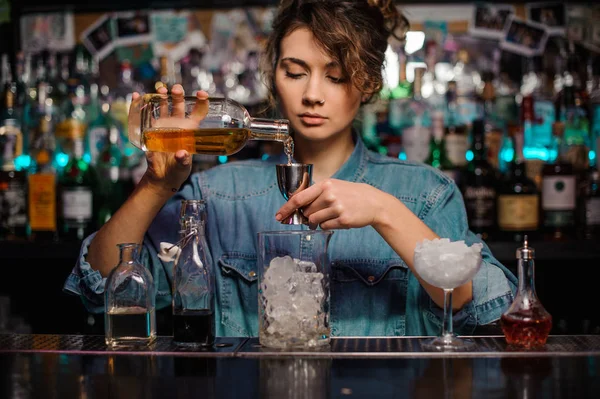 Vrouwelijke bartender gieten om de stalen jigger een alcoholische drank — Stockfoto