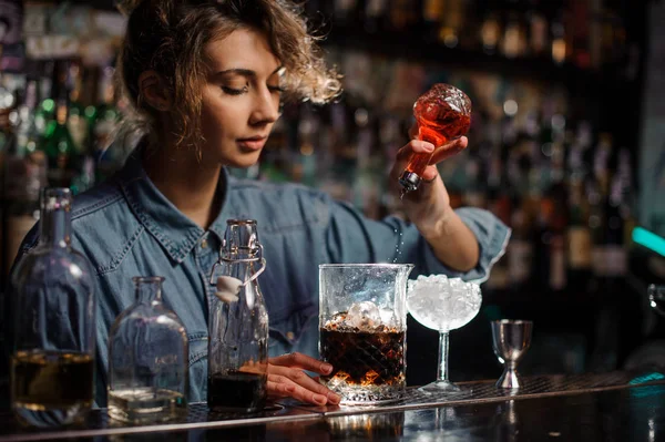 Mulher derramando para o copo de medição com cubos de gelo um amargo vermelho da garrafa de vidro — Fotografia de Stock