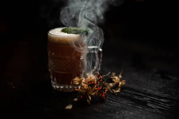 Bierglas mit alkoholischen Getränken, dekoriert mit Moos und geräucherten getrockneten Blumen — Stockfoto