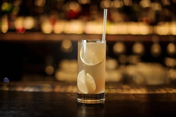 Bicchiere di cocktail di arancia alcolica fresca con fette di lime succose e paglia contro le luci — Foto Stock