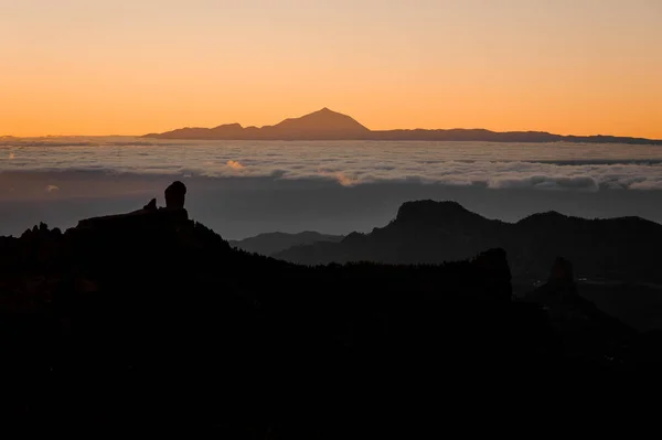 GRAN CANARIA, SPAIN - NOVEMBER 6, 2018: Morning landscape of Roque Nublo mountain under the orange misty sky and Tenerife island — Stock Photo, Image