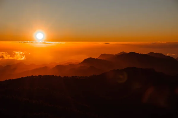 GRAN CANARIA, ESPANHA - NOVEMBRO 6, 2018: Colorido nascer do sol da montanha Roque Nublo sob o céu em névoa laranja brilhante — Fotografia de Stock