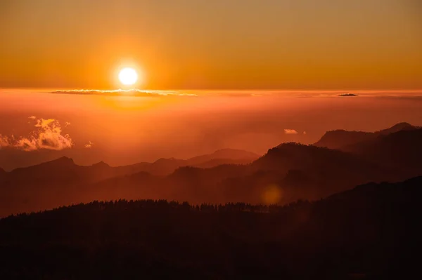 GRAN CANARIA, ESPANHA - NOVEMBRO 6, 2018: Brilhante crepúsculo da montanha Roque Nublo sob o céu em névoa laranja brilhante — Fotografia de Stock