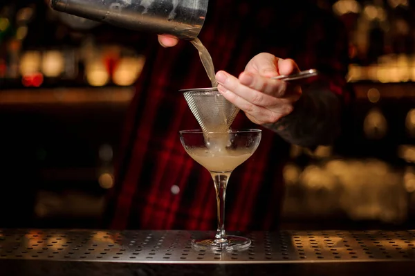 Barman sappige alcoholische cocktail van shaker gieten in cocktailglas — Stockfoto