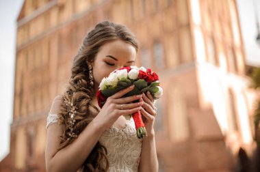 Bir gelinlik taze gül buketi koklama bir örgü saç modeli ile güzel gelin