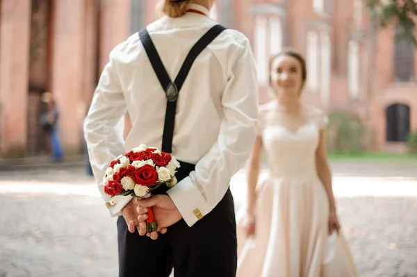 Voltar vista af um noivo segurando um buquê de casamento para sua noiva — Fotografia de Stock