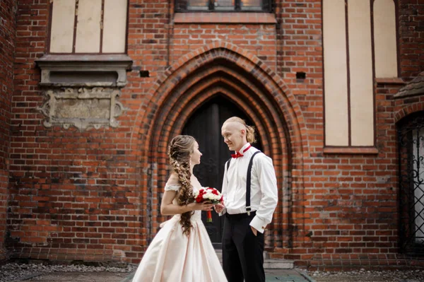 Casal elegante jovem casal de pé e sorrindo no fundo do antigo arco do edifício — Fotografia de Stock