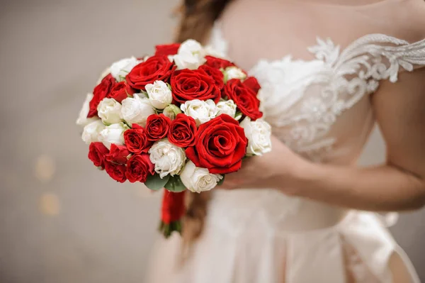 Joven novia en un vestido de novia con un ramo de rosas blancas y rojas — Foto de Stock