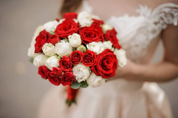 Noiva elegante em um vestido de noiva segurando um buquê de rosas brancas e vermelhas — Fotografia de Stock