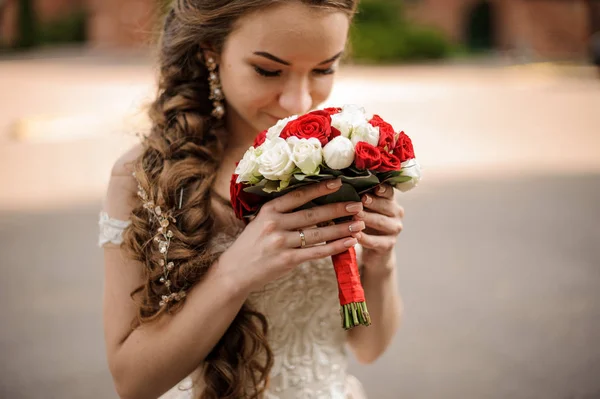 幸せな花嫁の赤と白のバラの花束をスニッフィング三つ編み髪型とウェディング ドレスの — ストック写真