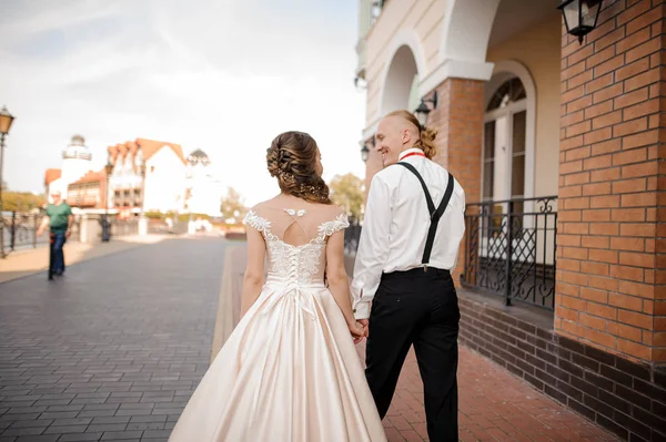 Back view of young and happy smiling married couple walking in town