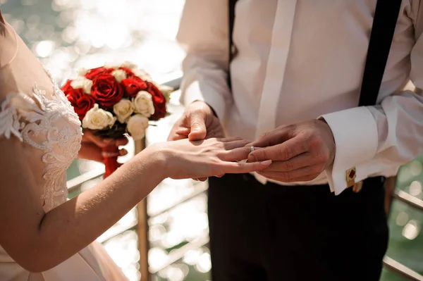 Vassoura colocando em um anel de casamento dourado para um dedo tenro noiva — Fotografia de Stock