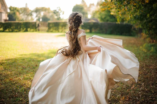 Widok z pięknej narzeczonej przędzenia w sukni ślubnej, taniec na zielonym polu tyłu — Zdjęcie stockowe