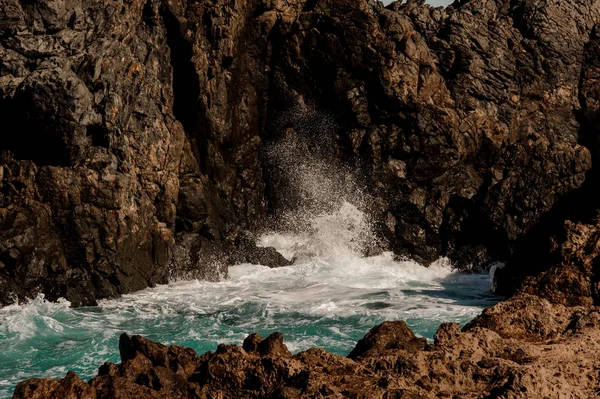 Rocha castanha alta com um mar azul tempestuoso — Fotografia de Stock