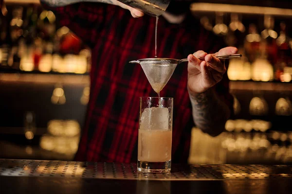 Barman pouring fresh orange drink into a glass