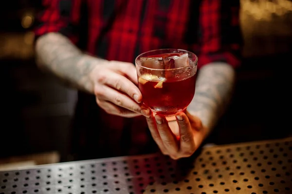 Barman sosteniendo una bebida alcohólica fuerte con whisky y cáscara de naranja — Foto de Stock