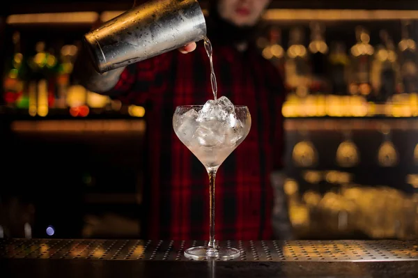 Bartendern hälla alkoholhaltig dryck i ett glas med isbitar — Stockfoto