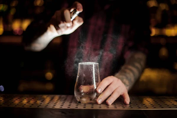 Barmann streut Bitterstoff in ein niedriges Cocktailglas — Stockfoto