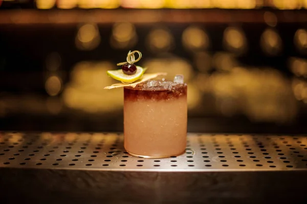 Élégant verre à cocktail rempli de savoureuses boissons alcoolisées sucrées avec des tranches de glace et de fruits — Photo
