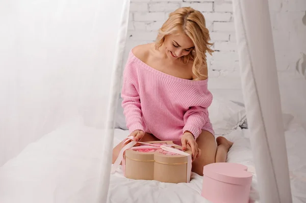 Flicka i rosa skjortan sitter på sängen med rutan i rosa blommor — Stockfoto
