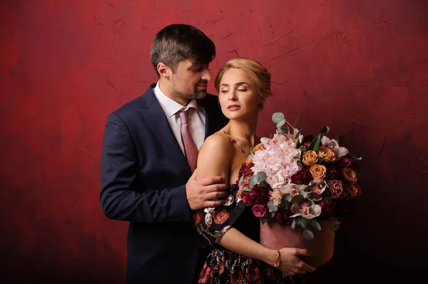 Młody człowiek przytrzymaj jego kobieta na ramię z bukietem kwiatów — Zdjęcie stockowe
