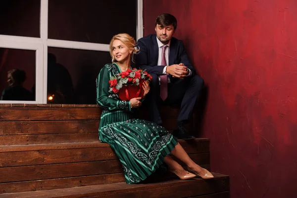 Młody mężczyzna i kobieta siedziała na schodach trzymając bukiet kwiatów, urocze — Zdjęcie stockowe