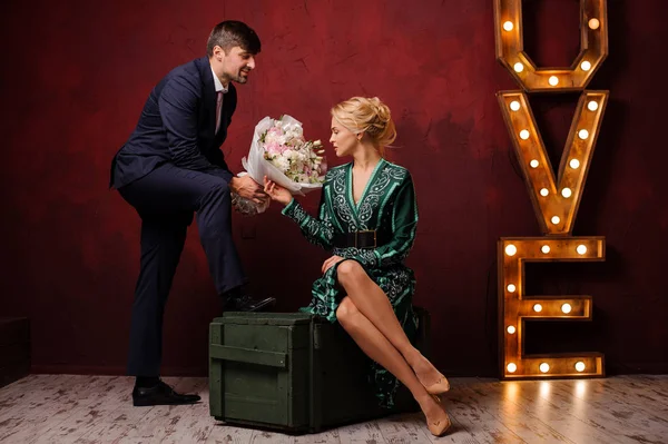 Fille dans la robe verte assis sur la boîte obtient un bouquet son homme — Photo
