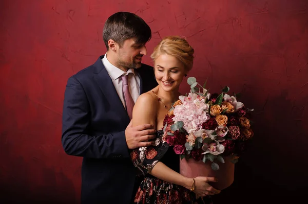 Uśmiechnięty mężczyzna uścisk jego kobieta z bukietem kwiatów — Zdjęcie stockowe