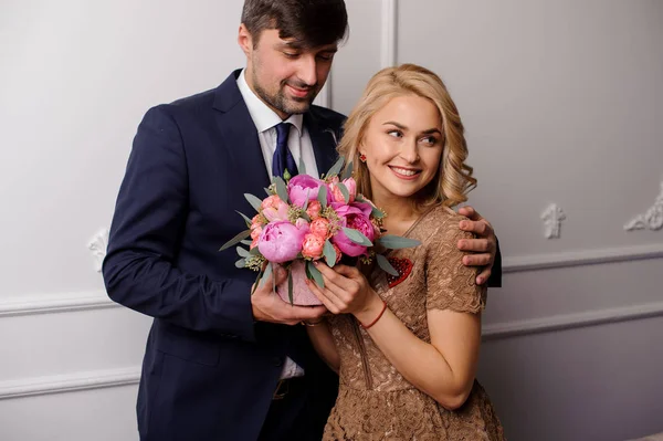 Młodego człowieka, przytulanie jego kobieta z bukietem kwiatów i patrząc w dół — Zdjęcie stockowe