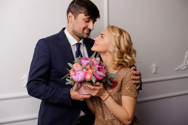 Ung man kramar hans kvinna med buketten av blommor och undersöker ögon — Stockfoto