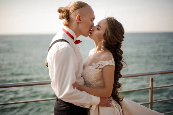 Apenas casado homem e mulher beijando uns aos outros no cais no lago — Fotografia de Stock
