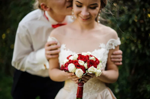 Frisch verheirateter Mann küsst Braut im grünen Park — Stockfoto