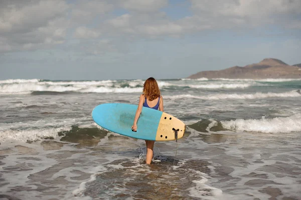 Menina desportiva no maiô azul andando com o surf — Fotografia de Stock