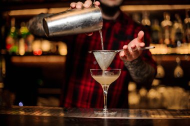 Taze ve tatlı sulu alkollü kokteyl shaker dan Süzgeç çubuğunu kullanarak kokteyl cam içine dökme barmen