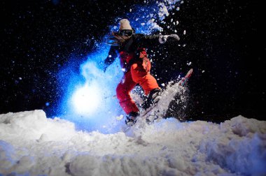 Dağ yamacında atlama kırmızı bir spor giyim giymiş kadın snowboard