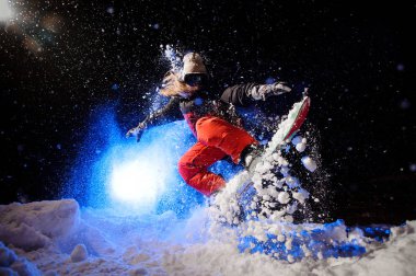 Dağ yamacında atlama bir portakal spor giyimli kadın snowboard