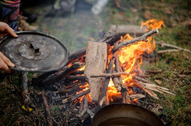 Kapak Pan kamp ateşi yakın yerleştirerek tutan adam