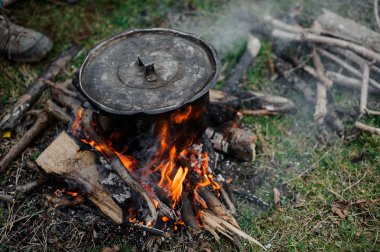 Siyah ormandaki şenlik ateşi üzerinde bir kapak duran ile pan