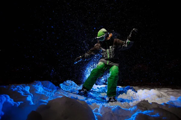 Сноубордистка одягнена в зелений спортивний одяг, що їде на схилі гори — стокове фото