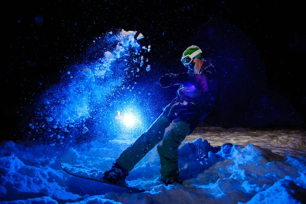 Active female snowboarder dressed in a green sportswear standind on the mountain slope — Stock Photo, Image