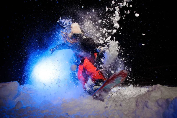 Aktive Snowboarderin in orangefarbener Sportbekleidung springt am Berghang — Stockfoto