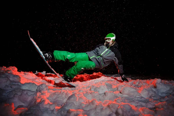 Aktive Snowboarderin in grüner Sportbekleidung auf der Bergschanze — Stockfoto