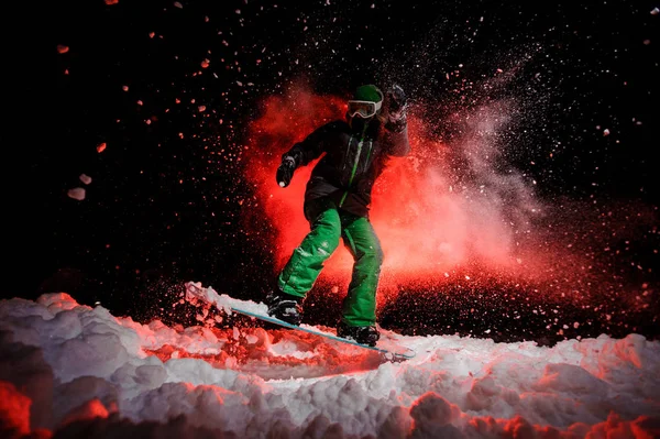 Mädchen auf dem Snowboard in grüner Sportbekleidung springt auf dem Schnee — Stockfoto