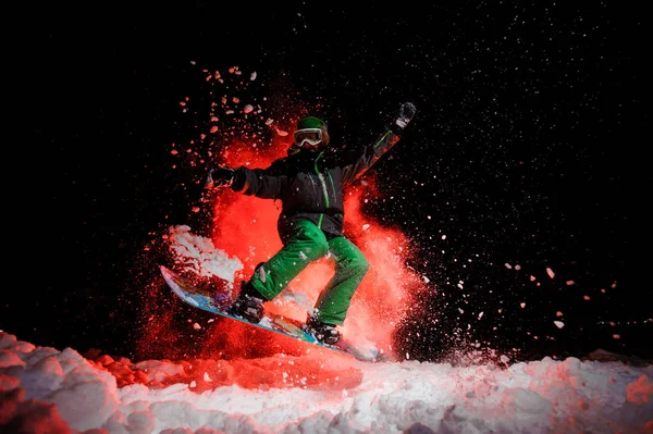 Femme active snowboarder vêtue d'un vêtement de sport vert sautant sous la neige — Photo