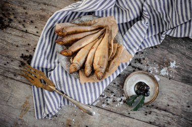 Yukarıdan duman kurutulmuş balık plaka gri çizgili gelmedi bir fırın kağıt üzerinde bir dekore altın çatal ile görüntüleyin