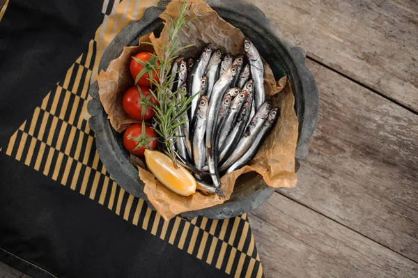 View from above on the fresh anchovies on the plate with a rosemary, cherry tomatoes and lemon — Stock Photo, Image