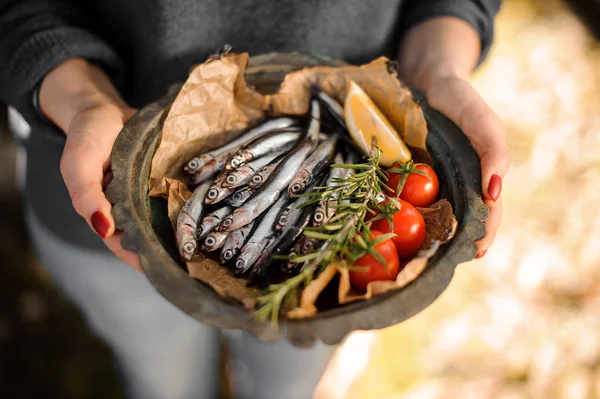 Woman holding a fresh anchovies on plate with a rosemary, cherry tomatoes and lemon — Stock Photo, Image