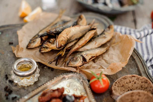 Sabroso pescado de jurel secado al humo en el papel con tomates secos y frescos, aceite y pan — Foto de Stock