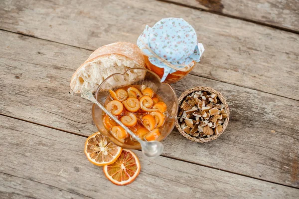 Vista desde arriba de la cáscara en espiral de naranja confitada con jarabe de azúcar en un frasco de vidrio y plato cerca del platillo con nueces — Foto de Stock